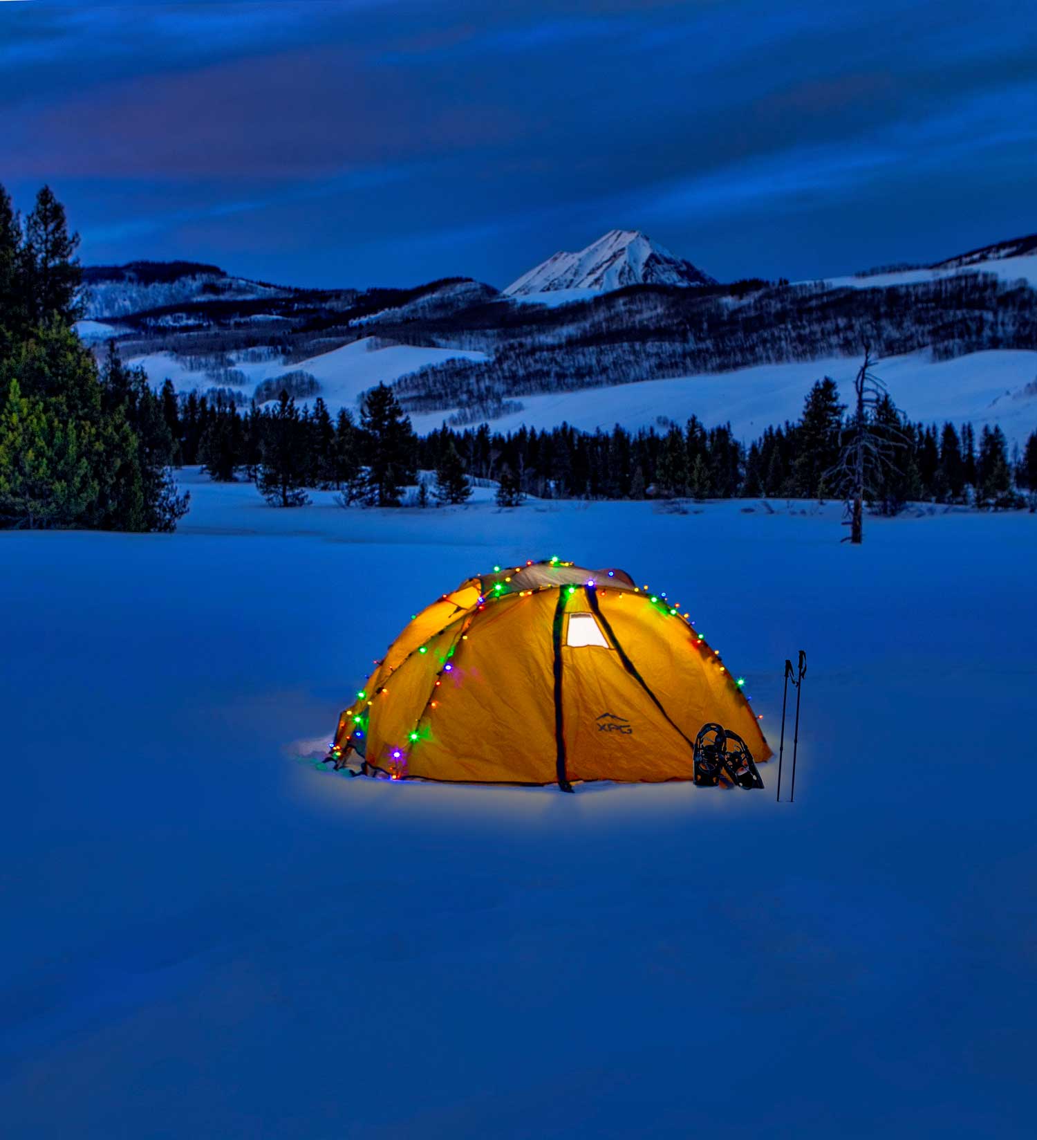 tent with lit up christmas lights on snowy mountain landscape